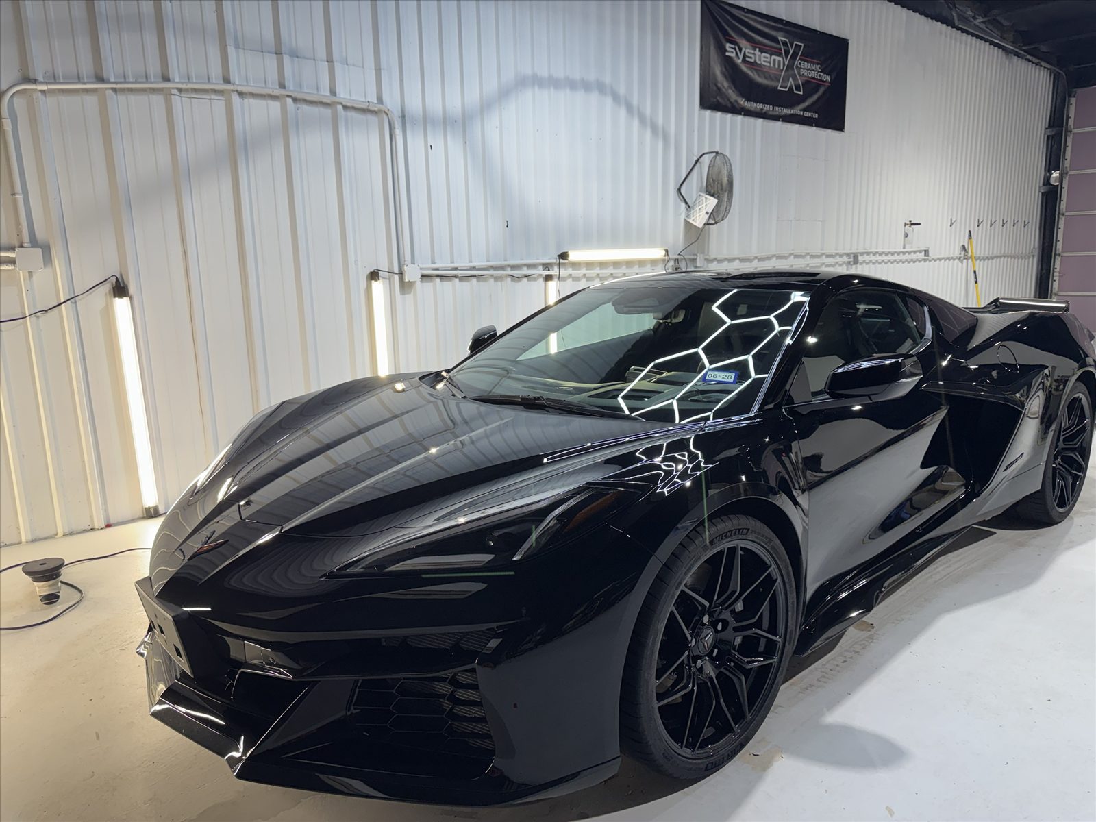 A black Corvette C8 receiving a System X ceramic coating install in the shop