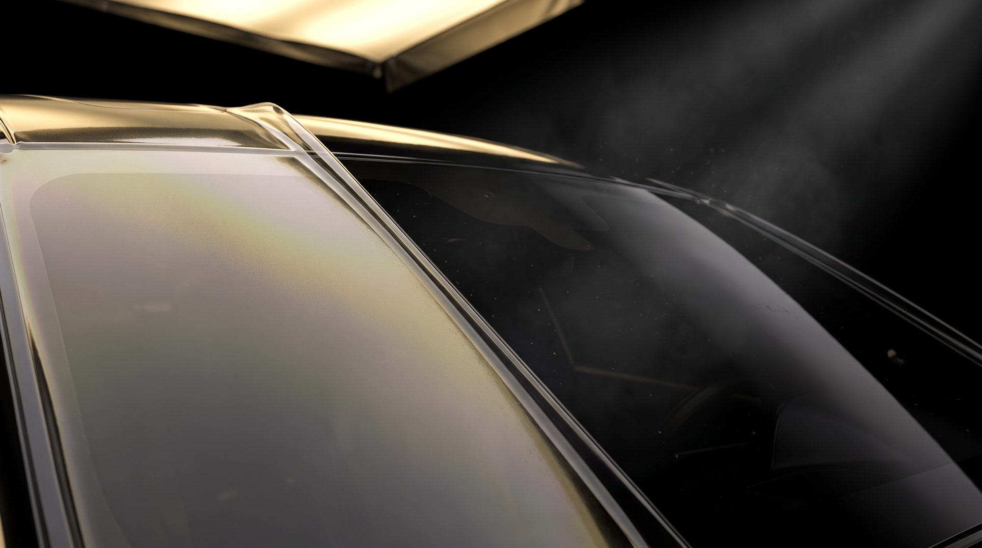 Paint protection film meeting bare clear coat across a glossy black panel, the film edge catching gold light